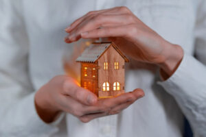 An image of someone holding a small model house representing the protection of short term rental insurance.